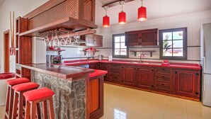 Cucina spaziosa con isola centrale, sgabelli rossi, mobili in legno e un'ampia finestra che offre luce naturale.