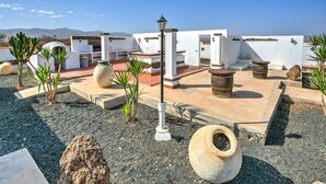 Un'area patio esterna con un muro bianco, gradini in pietra e diversi vasi.
