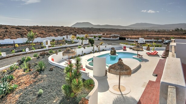 Un resort con piscina centrale, circondato da zone relax e un paesaggio desertico.