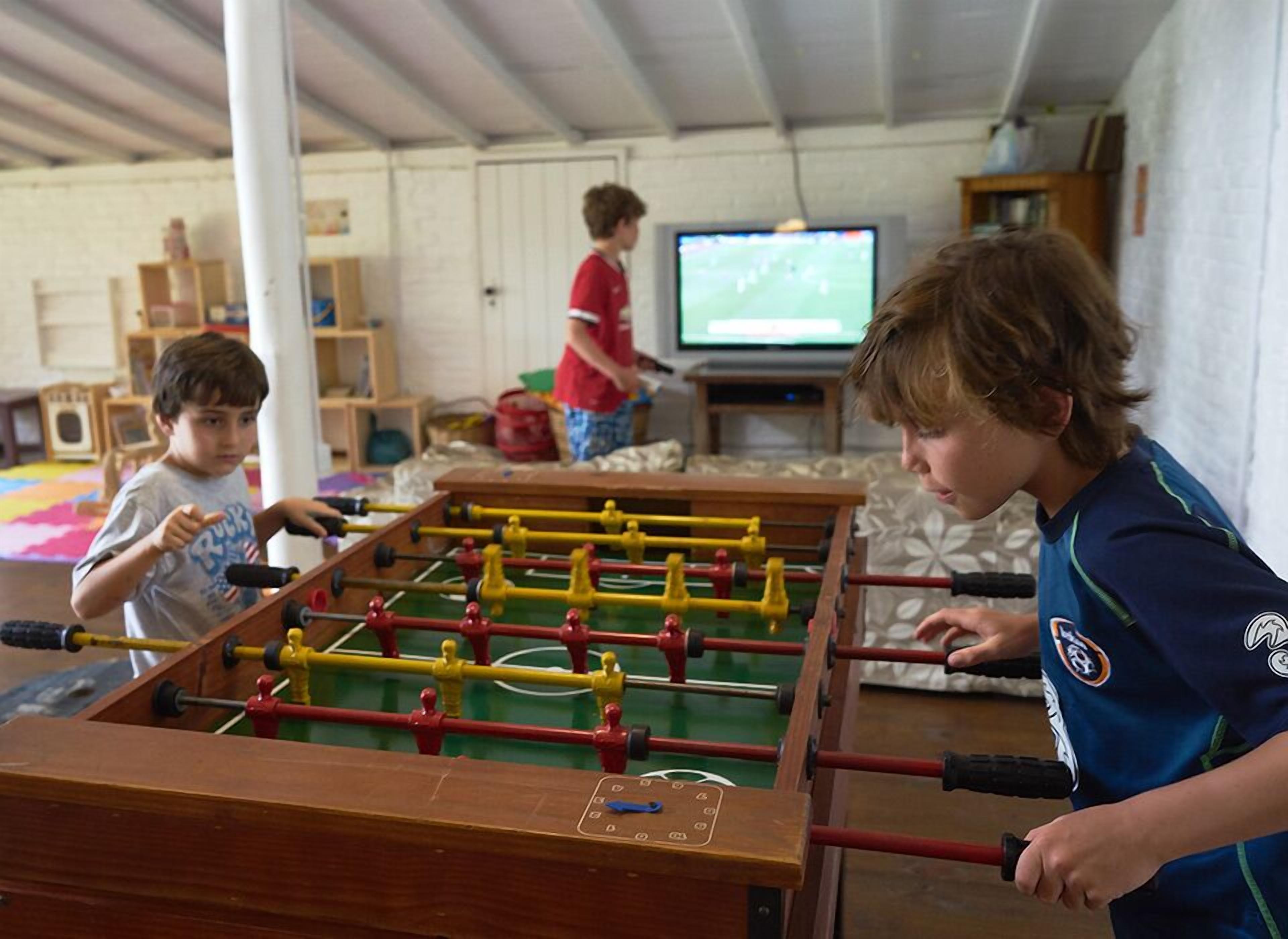 Une pièce équipée d’un baby-foot, d’une télévision et d’étagères remplies d’objets.