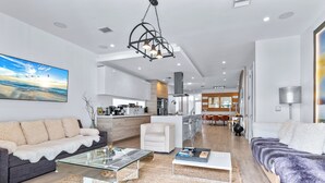 A modern living room with a sofa, coffee table, and a view of the kitchen and dining area. -  Blissful Coral Villa EcoPool4b-4b (Miami)