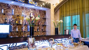 Ein Hotel-Empfangsbereich mit Marmorwand, einem digitalen Bildschirm und einem Buffet mit verschiedenen Speisen.