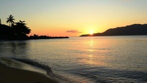 A beach at sunset with calm waters reflecting the sky. - Pouso Sambaquis (Ilhabela)