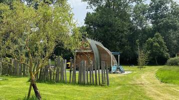 Escape to a serene cabin surrounded by lush greenery and trees, with a dirt path leading to the door.