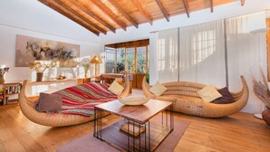 A spacious living room with a high wooden ceiling, large windows, and a view of greenery outside. - Unique House in Historical Center (Cuzco)
