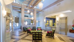 A spacious lobby with a high ceiling, wooden beams, and a central seating area with patterned chairs and a table. - Full Moon Lagoon by VillaDirect (Davenport)