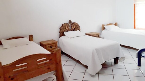 A room with two wooden beds, white bedding, a small wooden nightstand, and a tiled floor. - Beautiful country house (Jocotepec)