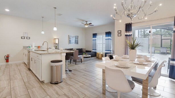 A modern kitchen with a central island, dining area with white chairs, and a chandelier. - Home Away from Home by VillaDirect (Davenport)