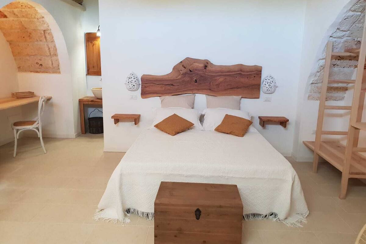 A bedroom with a large bed, wooden headboard, bedside tables, and a small wooden chest.