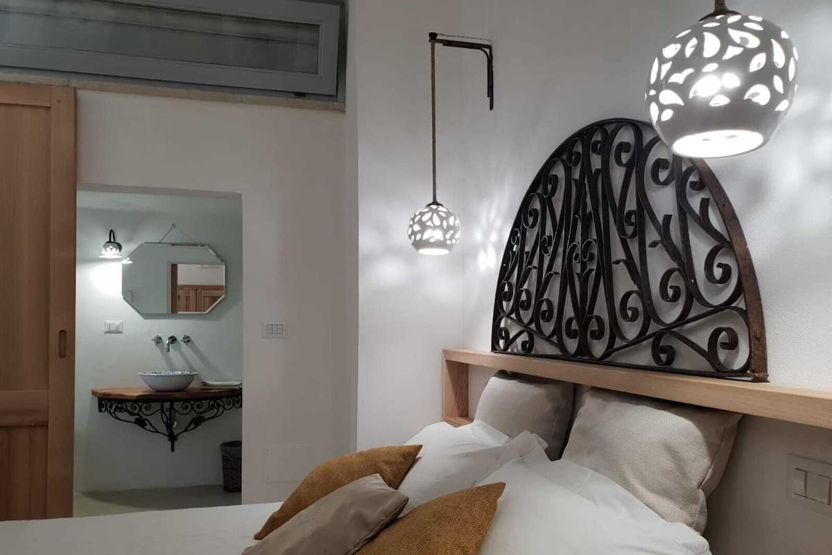 A bedroom with a bed, bedside lamps, a mirror, and a wooden headboard.