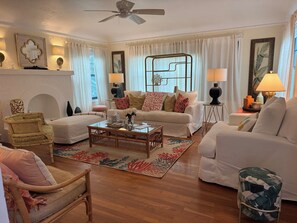 A living room with a sofa, armchairs, a coffee table, and a patterned rug.