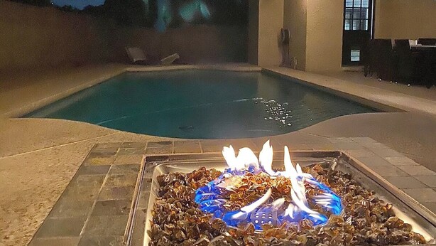A swimming pool with a fire feature in the center, surrounded by stone tiles. - Spacious Mesa Oasis with FREE Heated POOL (Mesa)