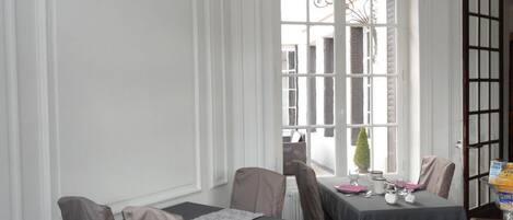 A dining area with two tables, chairs, and a window with a view of buildings.