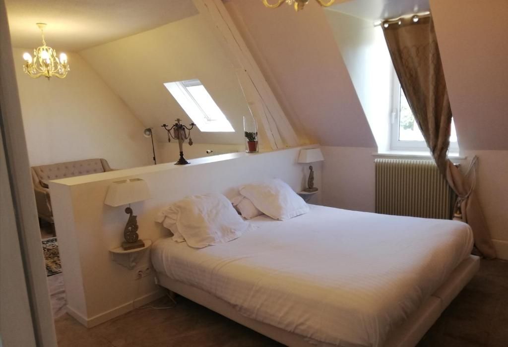 A bedroom with a single bed, a nightstand, a lamp, a mirror, and a window with curtains.