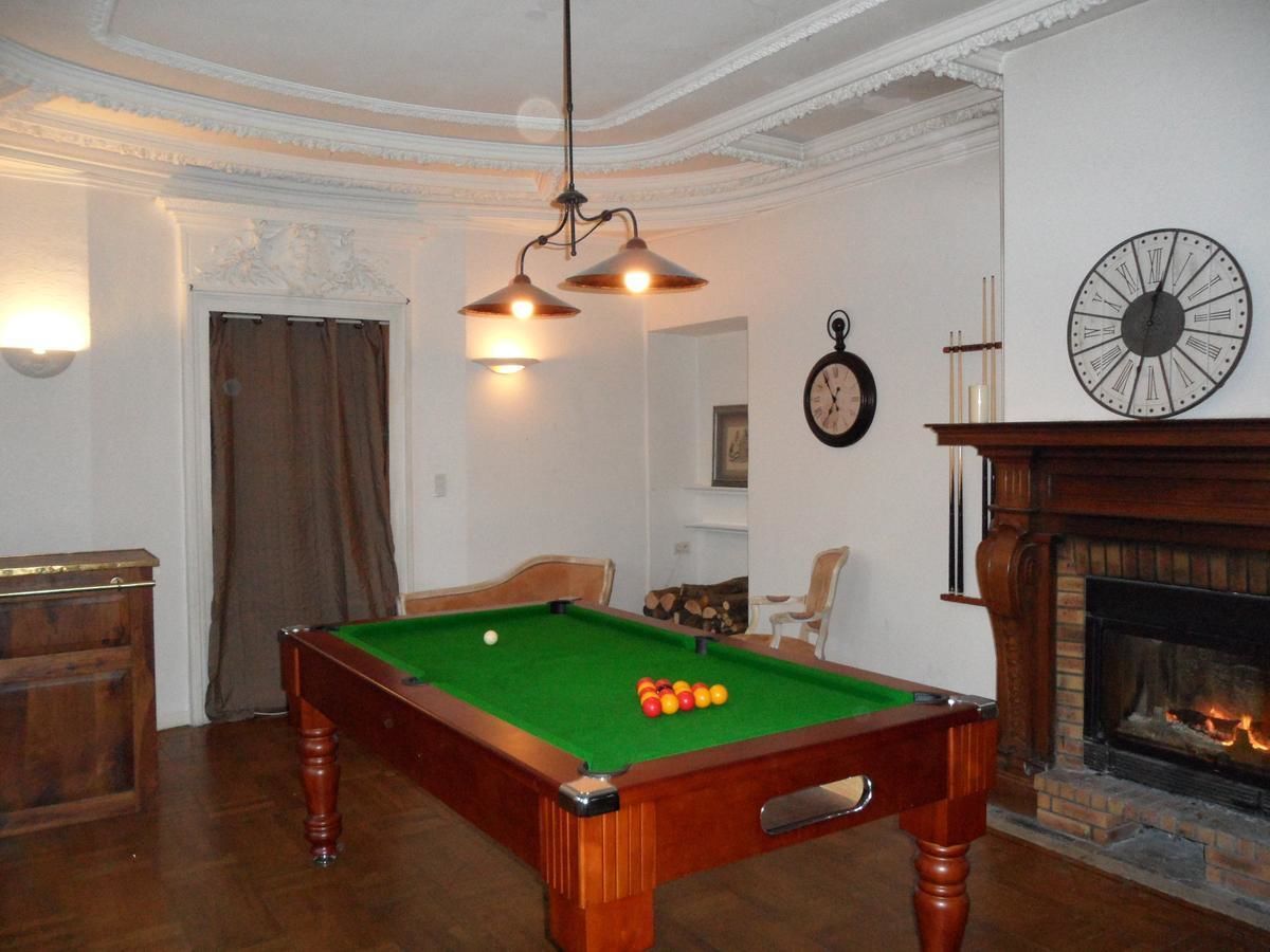 Une pièce avec une table de billard, une cheminée et une horloge au mur.