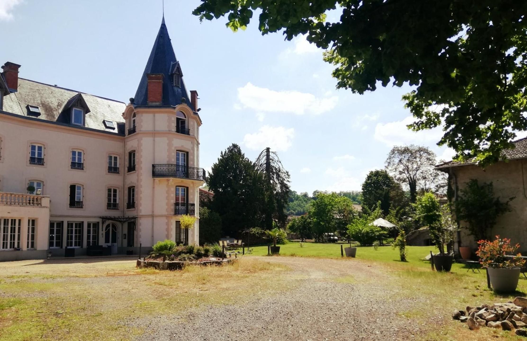 A large building with a tower, surrounded by a gravel courtyard and greenery.