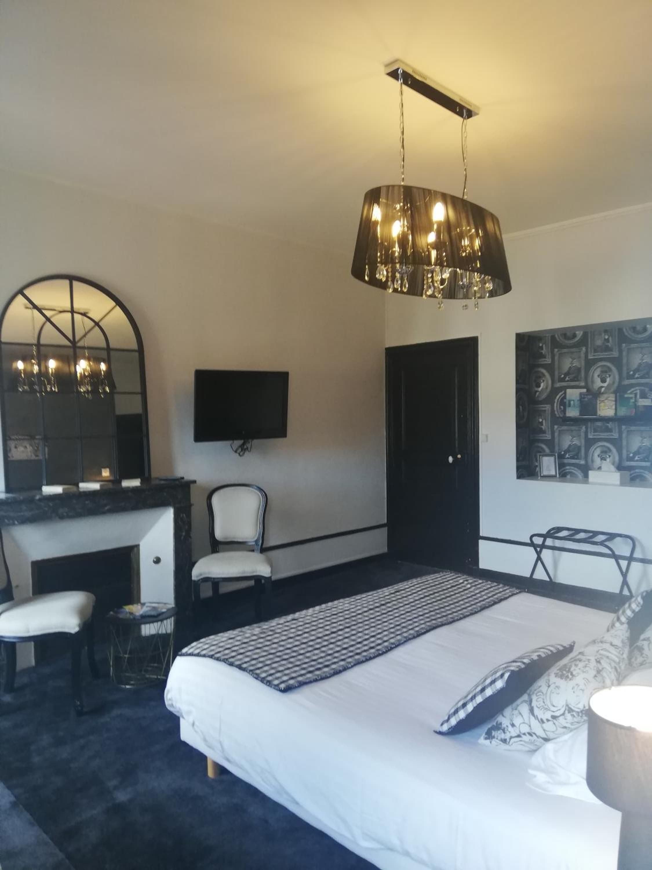 A bedroom with a bed, a desk with a chair, a television, and a wall-mounted mirror.