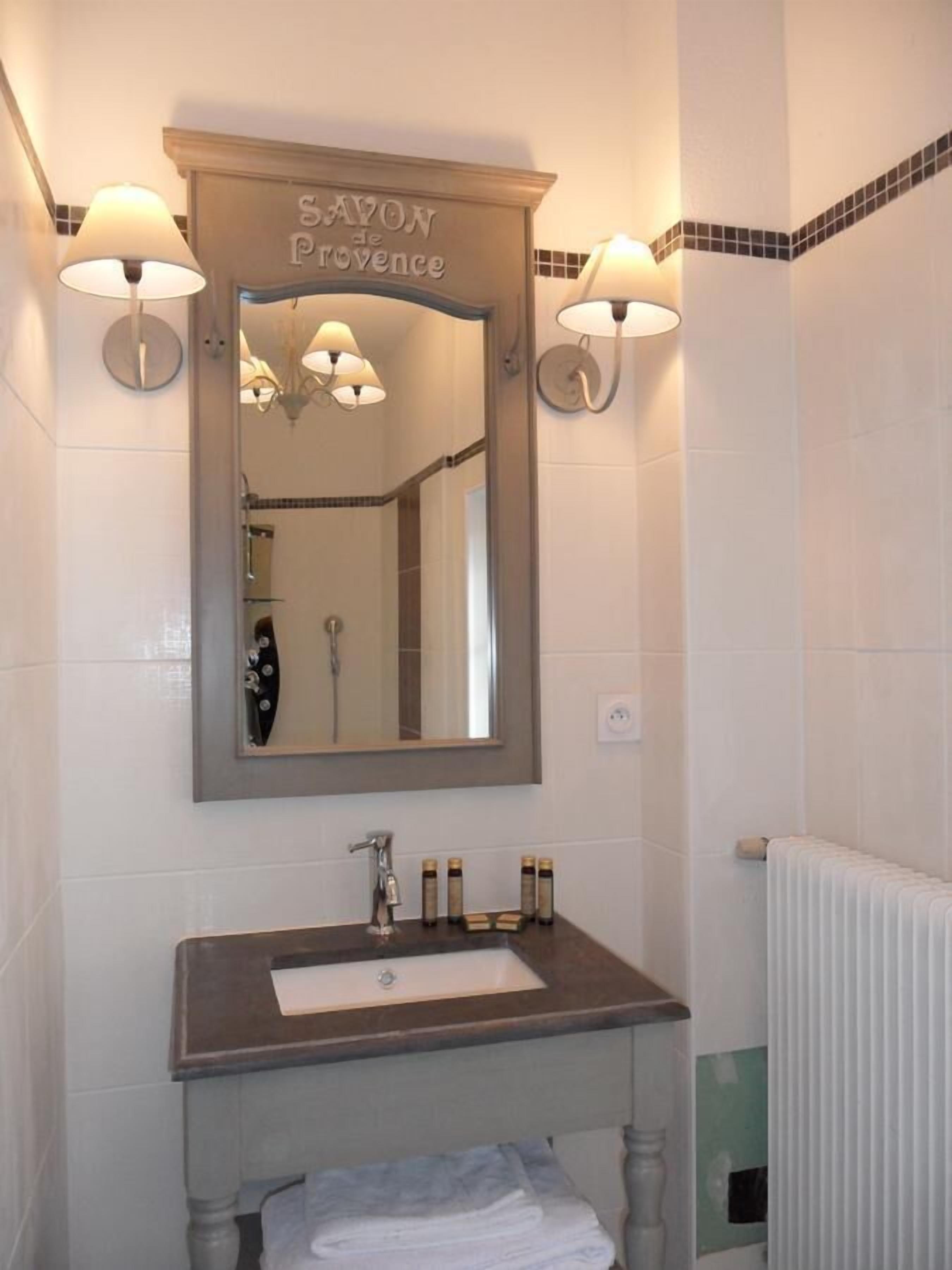 Een badkamer met een wastafel, een spiegel en wandlampen.