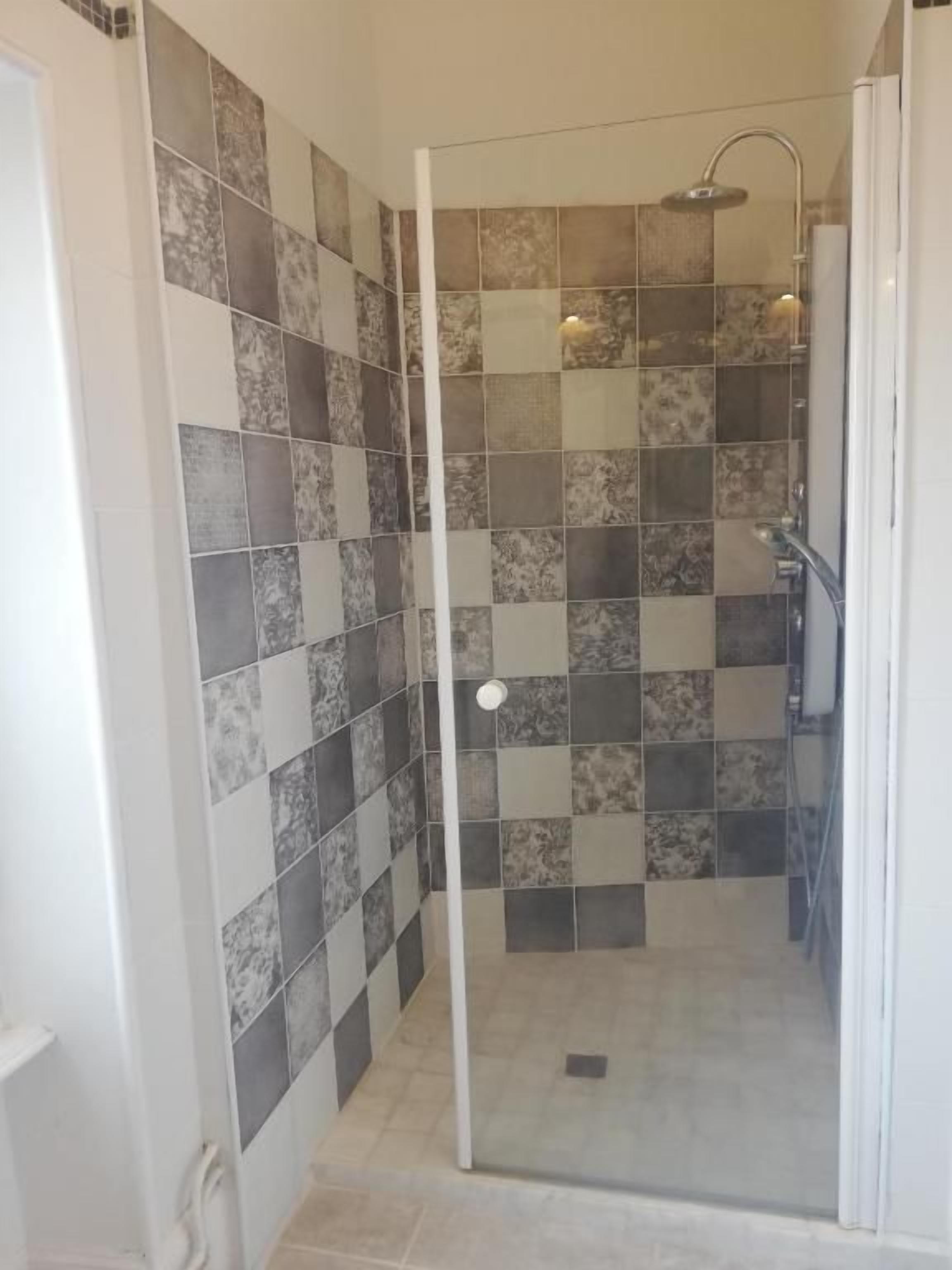 A shower area with a glass door, tiled walls, and a showerhead.