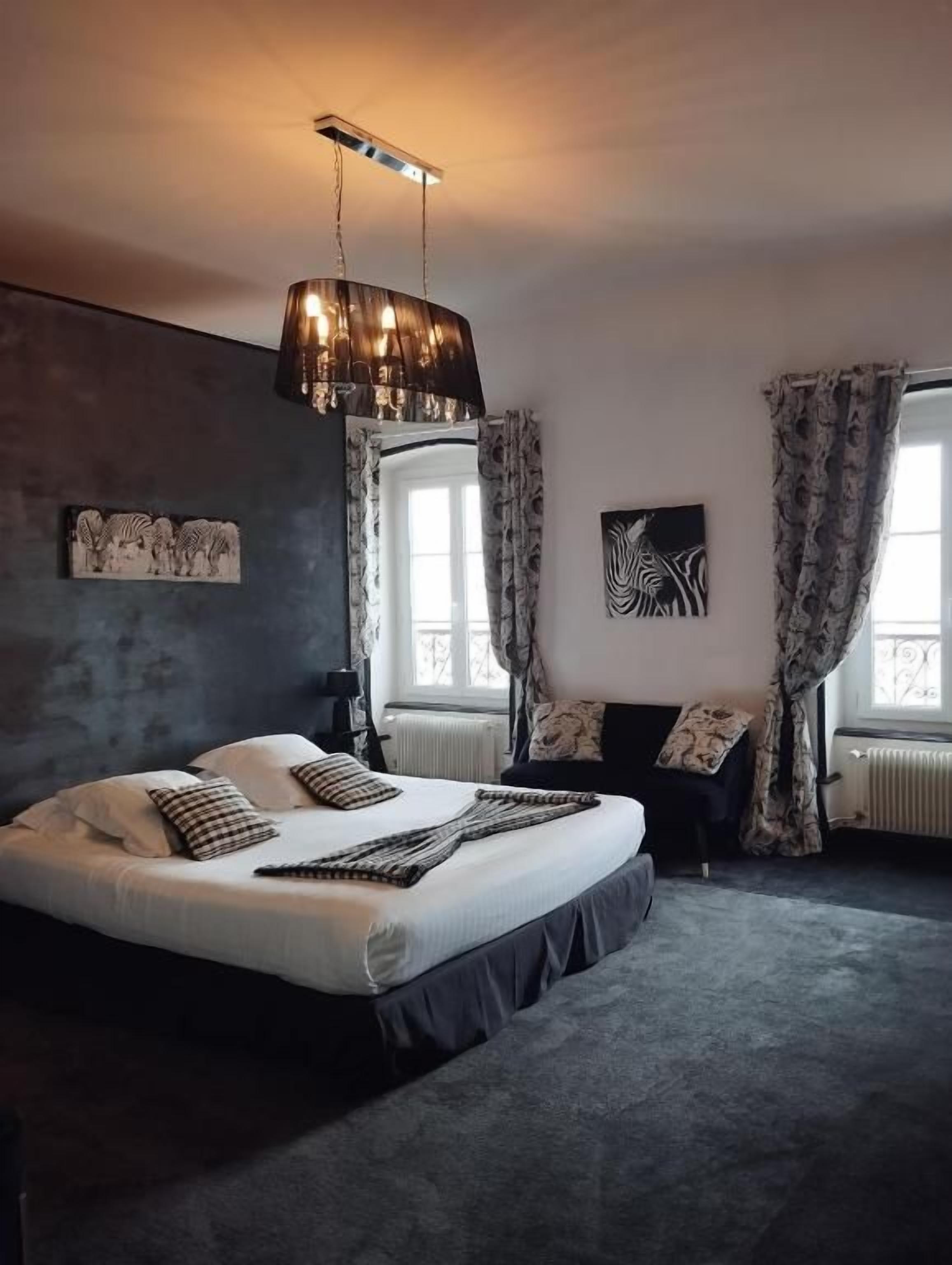 Ein Schlafzimmer mit einem großen Bett, einer Hängeleuchte und einem Fenster mit Vorhängen.