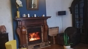 A living room with a fireplace, a yellow armchair, a brown sofa, a coffee table, and a hanging light fixture. - Chateau les 4 saisons (Saint-Cirgues-sur-Couze)