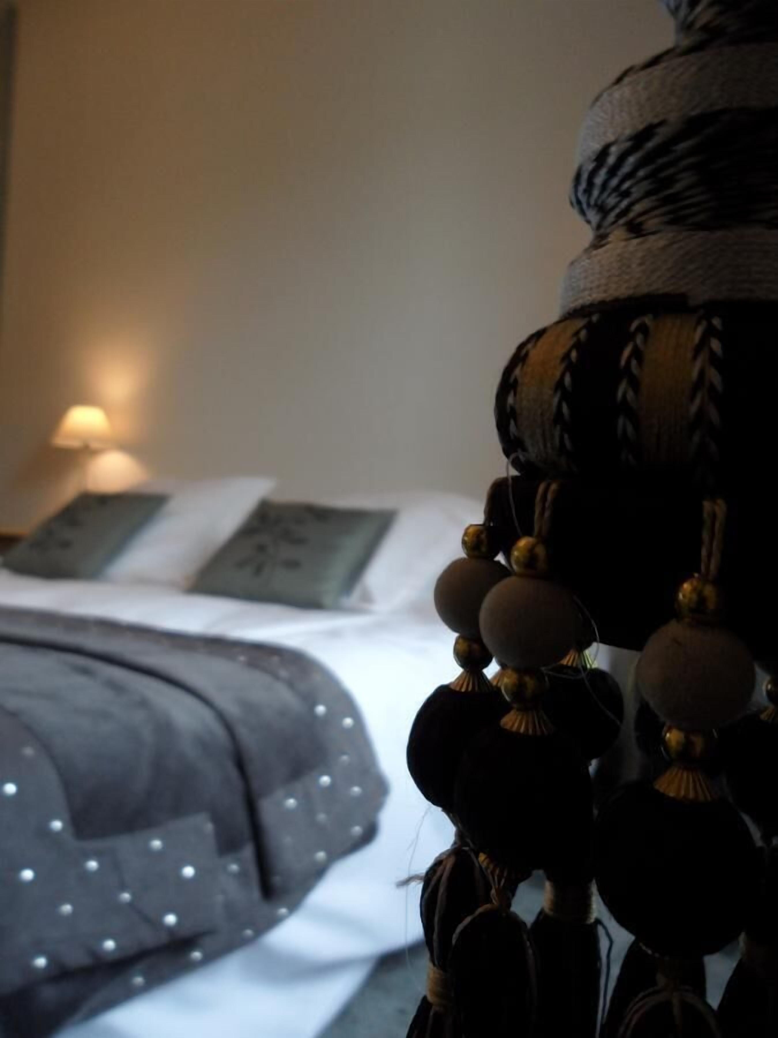 Ein Bett mit einer dunkelgrauen gepunkteten Decke, einem weißen Kopfkissen und einer Wandlampe.