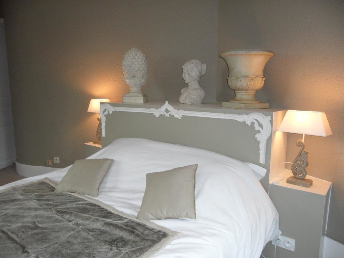Un dormitorio con una cama, dos lámparas de noche y objetos decorativos en la mesita de noche.