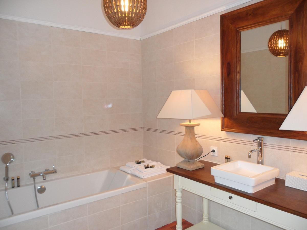 Une salle de bain équipée d’une baignoire, d’un lavabo, d’un miroir et d’un luminaire fixé au mur.
