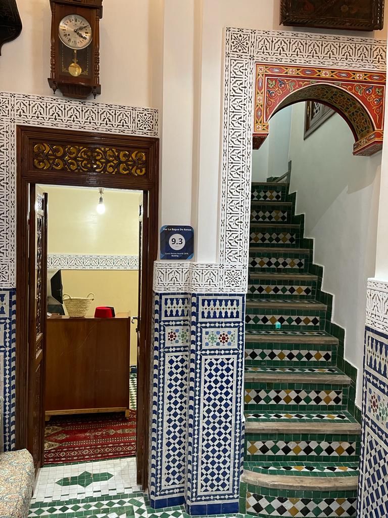 A staircase with intricate tile patterns, a wooden door, and a clock on the wall.