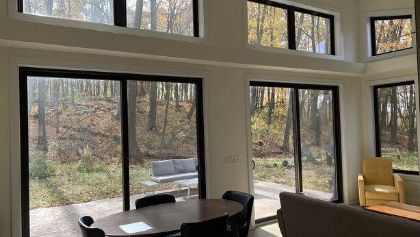Un intérieur moderne avec de grandes portes-fenêtres coulissantes donnant sur un espace extérieur arboré.