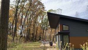 Une maison moderne dotée d’une grande fenêtre, entourée d’une forêt.