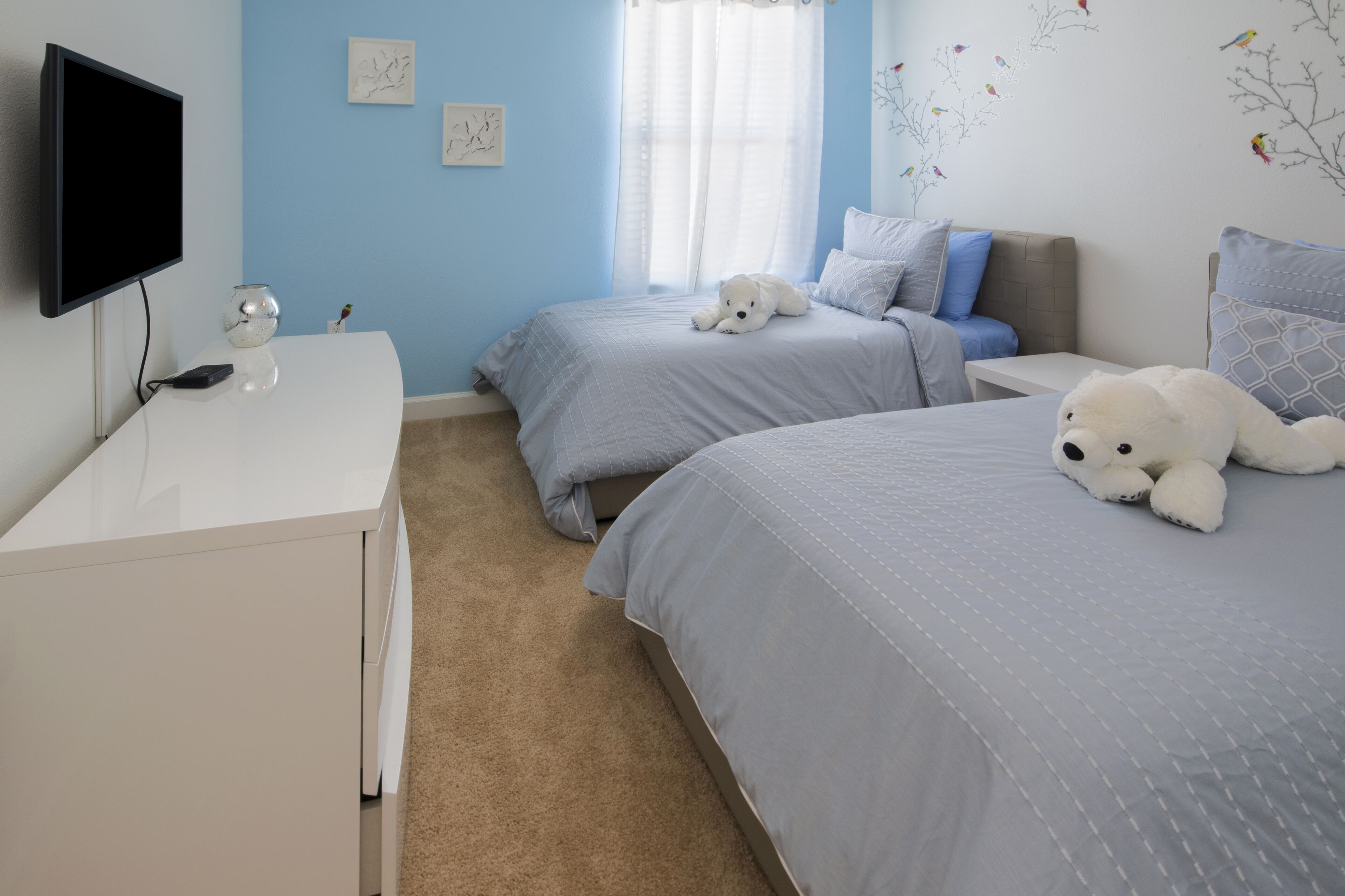 A bedroom with two beds, a TV, and a desk.