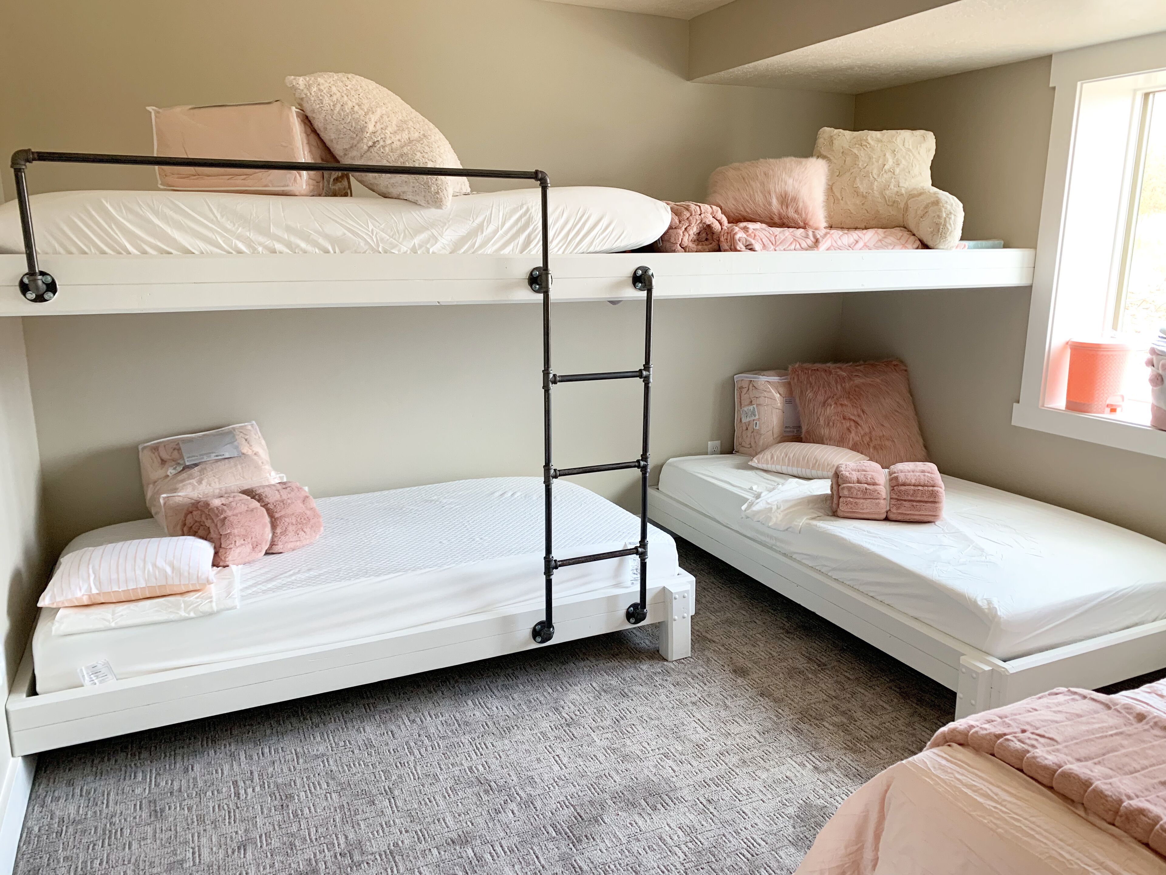 Une chambre avec un lit superposé à deux niveaux, chaque niveau étant équipé d’un matelas, d’oreillers et d’une couverture. Une échelle relie les deux lits, et il y a une fenêtre avec vue.