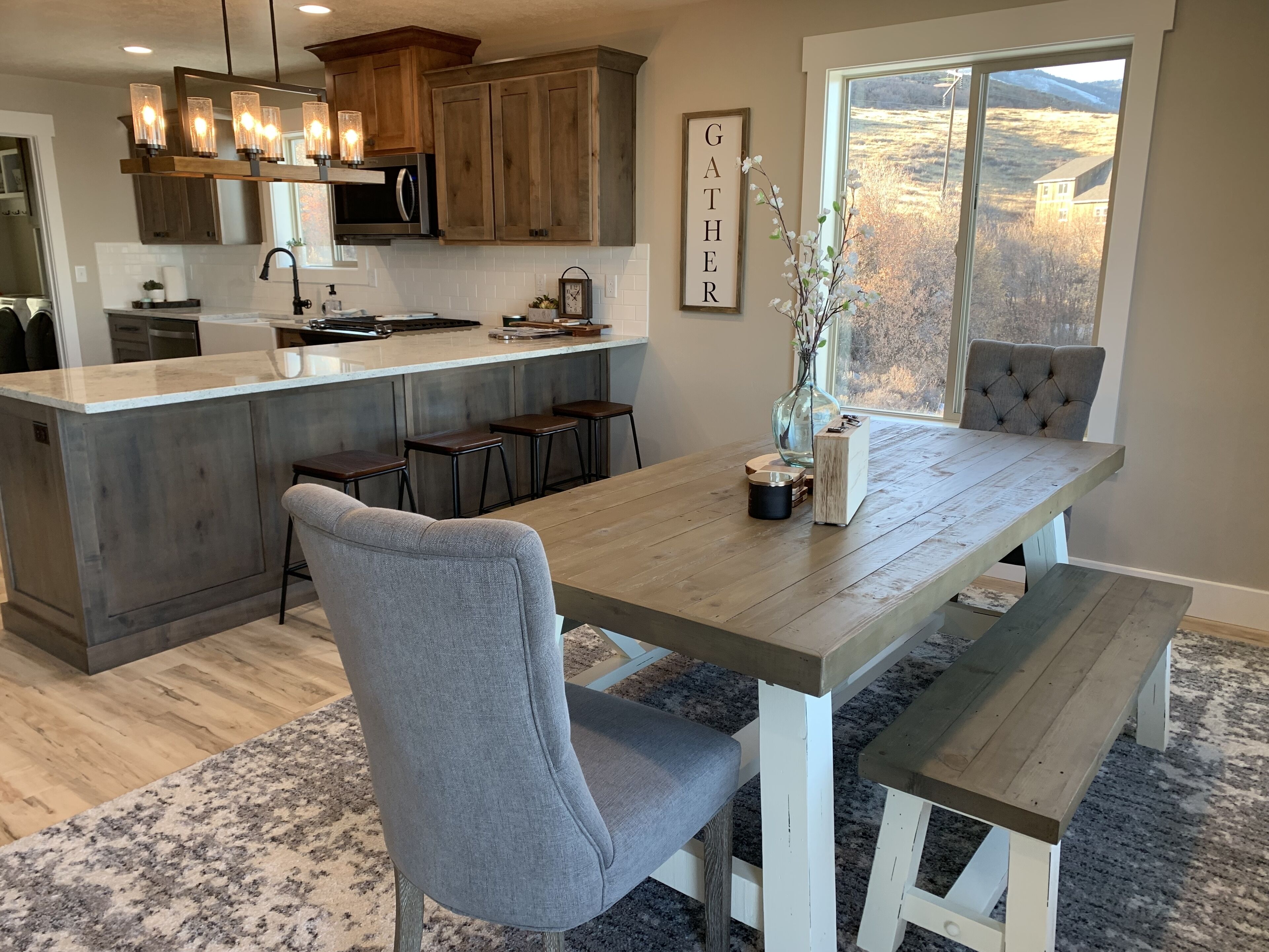 Una cocina moderna con una isla central, taburetes de bar y una mesa de comedor con bancos.
