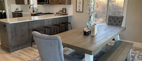 Una cocina moderna con una isla central, taburetes de bar y una mesa de comedor con bancos.