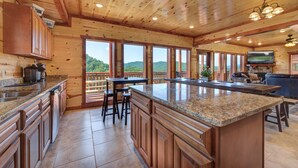 A spacious kitchen with granite countertops, wooden cabinets, and a large island. - Private Heated Indoor Pool, Mountain View, Hot Tub, Pigeon Forge Cabin, Pool Table, Theater Room (Sevierville)