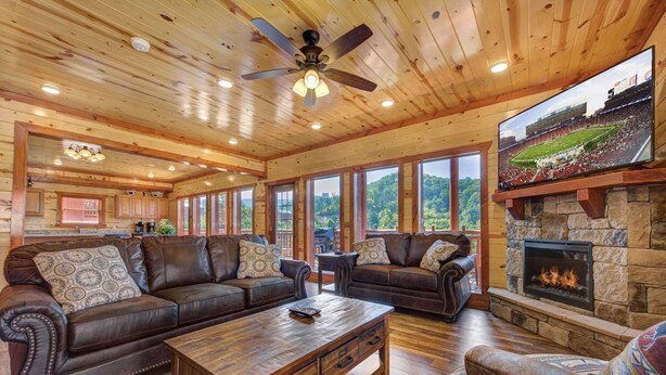 A spacious living room with a large wooden ceiling, a fireplace, and a television mounted on the wall. - Private Heated Indoor Pool, Mountain View, Hot Tub, Pigeon Forge Cabin, Pool Table, Theater Room (Sevierville)