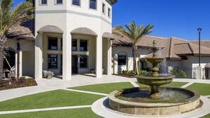A building with a fountain in the courtyard, surrounded by well-maintained grass and palm trees. - Mickeys Hideaway by VillaDirect (Davenport)