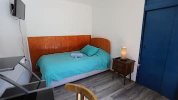 Une chambre à coucher avec un lit, un bureau, une chaise, une table de chevet avec une lampe et une porte bleue.