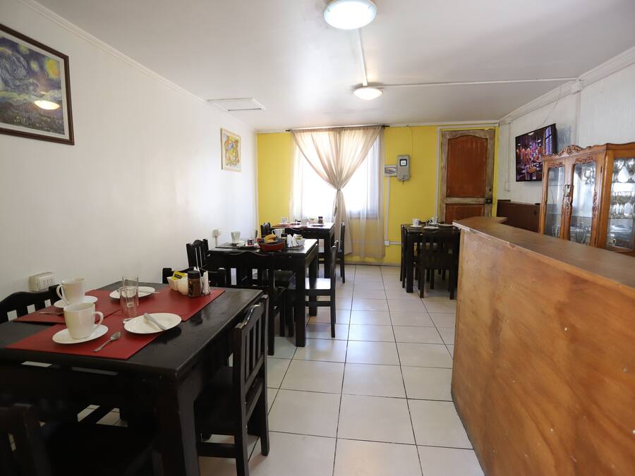 A dining area with tables, chairs, a wooden counter, and a painting on the wall.