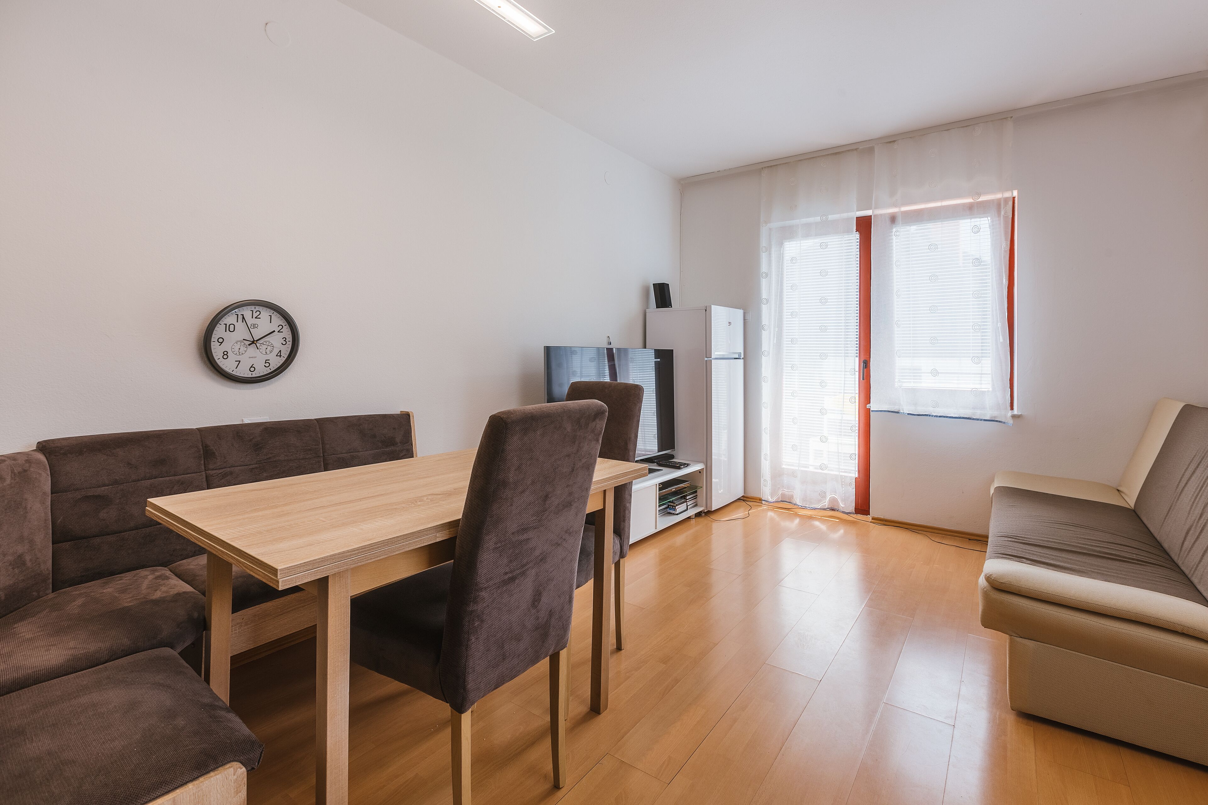 A modern living room with a sofa, a dining table, and a TV.