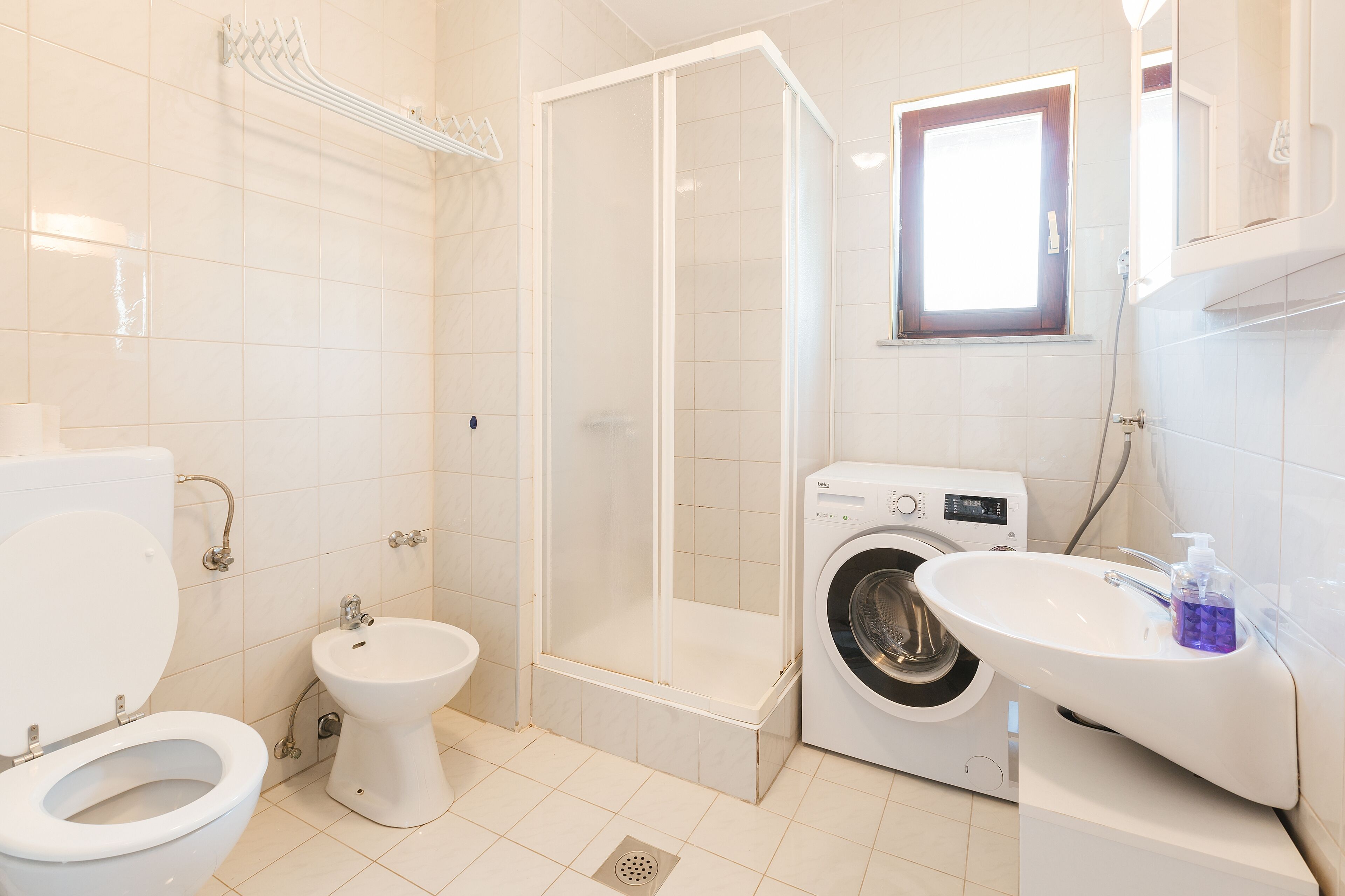 A modern bathroom with a toilet, bidet, shower, and washing machine.
