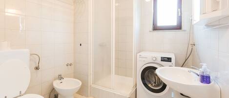 Un baño moderno con inodoro, bidé, ducha y lavadora.