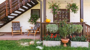 Un escalier en bois mène à une véranda où se trouvent deux chaises et une table.