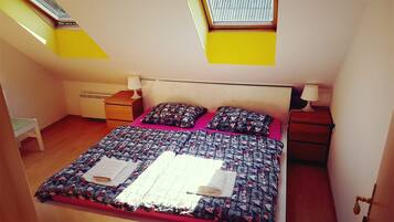 Een slaapkamer met een bed, twee nachtkastjes, een stoel en een dakraam.