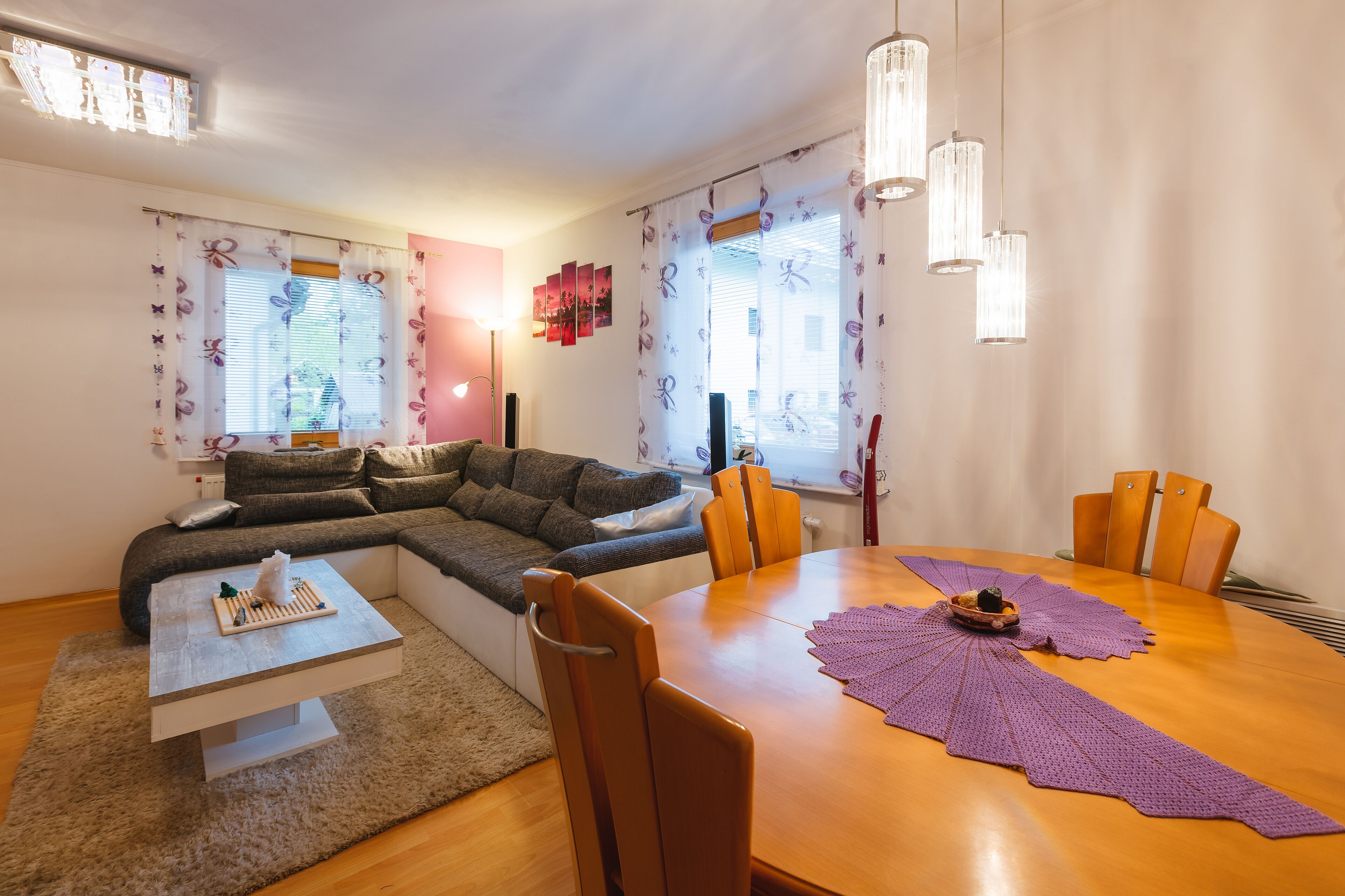 A modern living room with a wooden dining table, a sofa, and a coffee table.