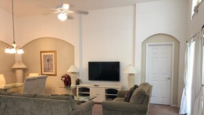 A living room with two sofas, a TV, and a white door. - Relax with a lake view, pool and Jacuzzi (Kissimmee)