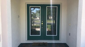 A green double door with a white frame, a doormat with the word "hello", and a brick entrance. - Relax with a lake view, pool and Jacuzzi (Kissimmee)
