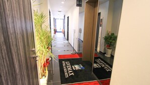 A hotel corridor with a red and black carpet, potted plants, and a sign indicating the direction to the lobby. - HOTEL LiVEMAX Kyoto Teramachidori (Kyoto)