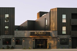 A modern building with a prominent 'FOUND' sign, featuring a mix of vertical and horizontal wooden panels, large windows, and a brick facade. - FOUND Hotels, Santa Monica, Series by Marriott (Los Angeles)